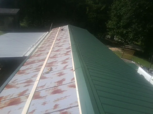 Old rusted panels beside newly installed green metal roofing — Wind Damage Roof Repair by Roofing Brothers in Camarillo