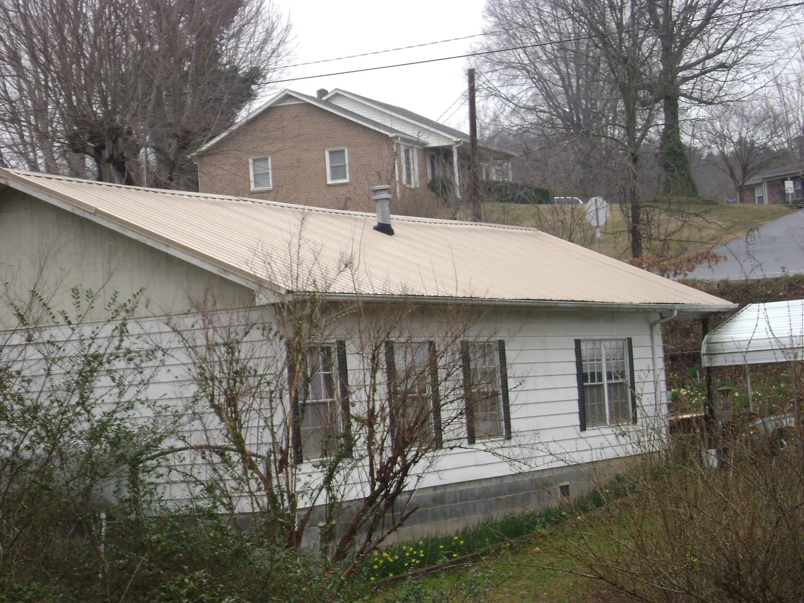 Tan metal roof on a white sided house set into a hillside — Commercial Roofing by Roofing Brothers in Camarillo