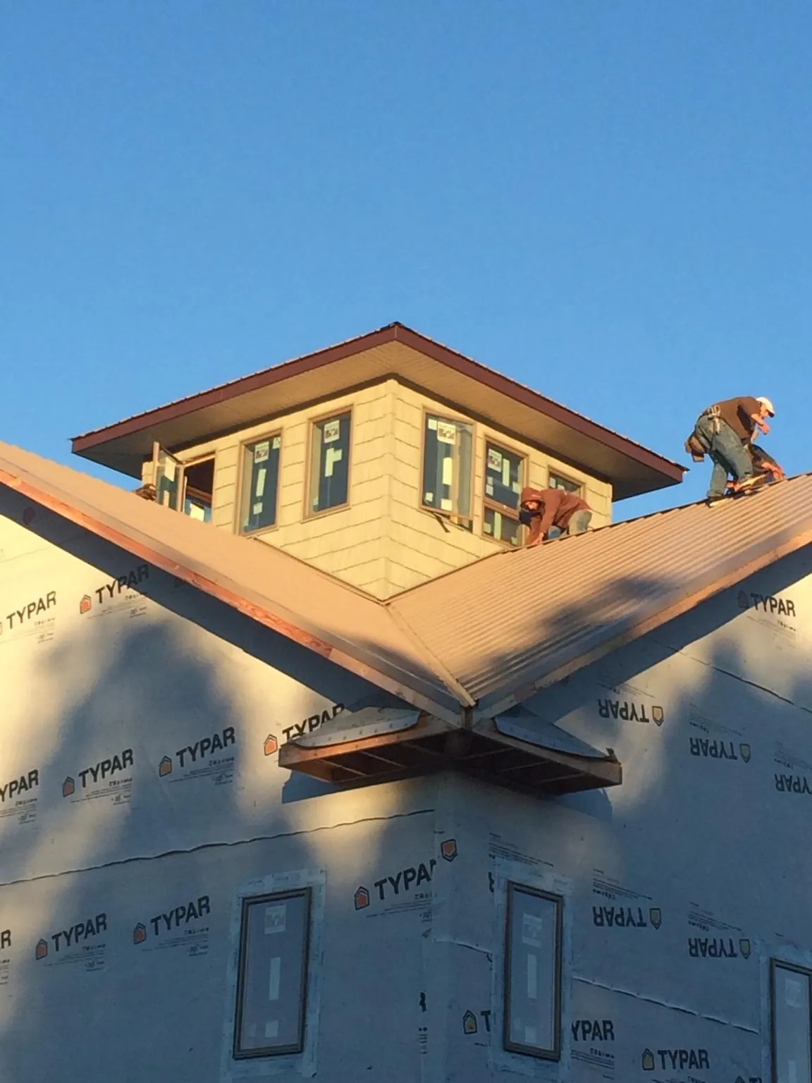 Roofers working around a rooftop cupola on a new metal roof at sunset — Roof Waterproofing in Camarillo by Roofing Brothers
